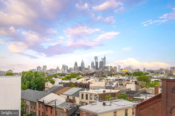 Panoramic view of a city skyline with scattered buildings and cloudy sky.