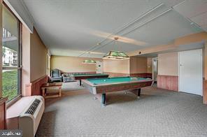 Indoor recreation room with billiards tables and seating area.