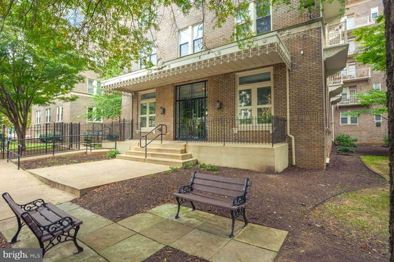 Front view of a brick apartment building with steps leading to a glass door entrance.
