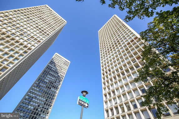 Upward view of three tall buildings with a grid pattern facade against a blue sky.