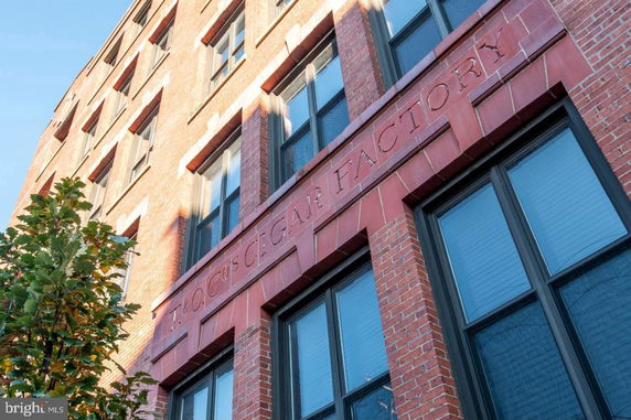 Front view of a brick building with 'Cigar Factory' inscribed above the windows.