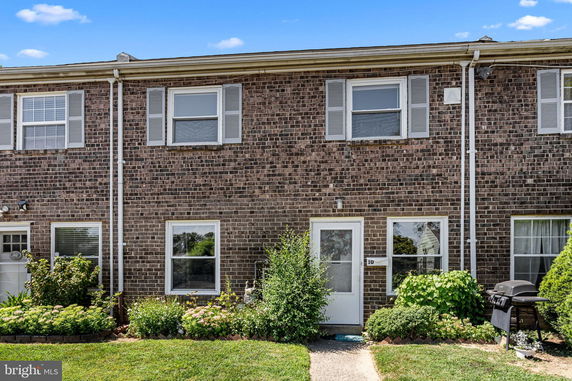 Front view of a two-story brick townhouse with white trim windows and a central entrance.