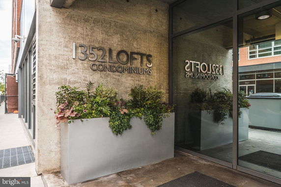 Front view of a condominium building with a concrete facade and reflective glass entrance.