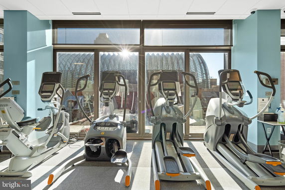 Indoor gym area with exercise equipment facing large windows.