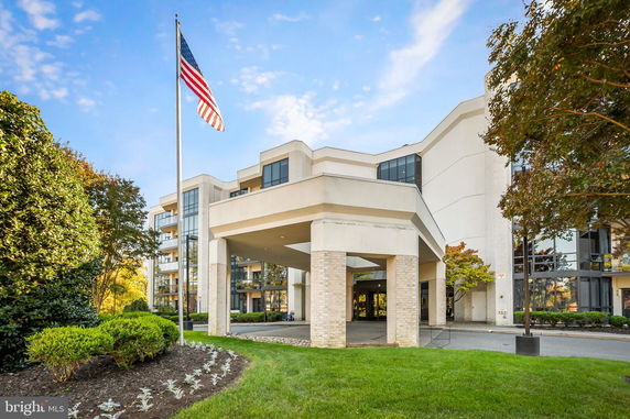 Front view of a multi-story building with a covered entrance and flagpole.