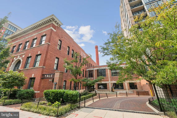 Front view of a multi-story brick building with tall windows and an arched entrance.
