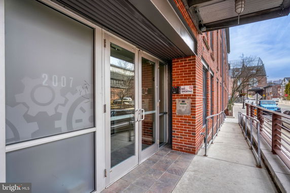 Entrance view of a brick building with glass doors and a 'No Smoking' sign.