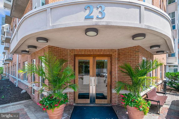 Front view of a building entrance with a brick facade and canopy, marked with the number 23.