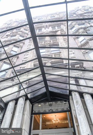 View of a multi-story building with ornate architectural details seen through a glass canopy.