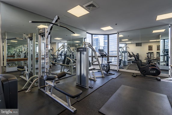 Interior view of a modern gym with various fitness equipment and mirrored walls.