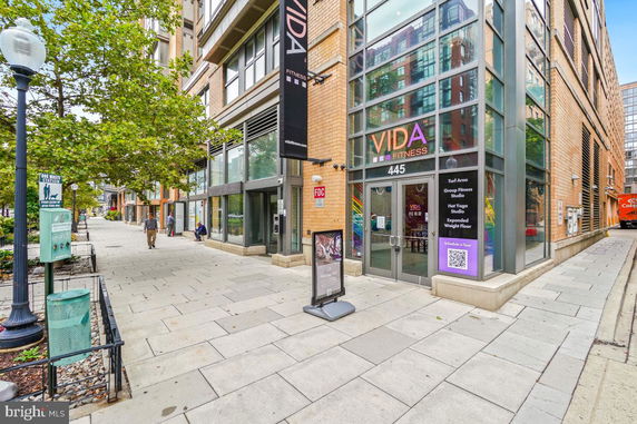 Front view of a modern multi-story building with large glass windows and a fitness center entrance.