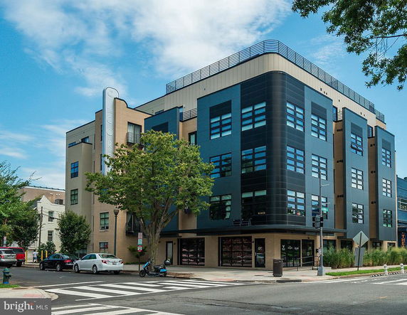 Front view of a modern multi-story building on a corner with blue and beige facade.