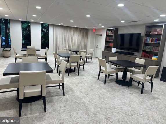 Indoor recreation area with tables, chairs, a TV, and bookshelves.