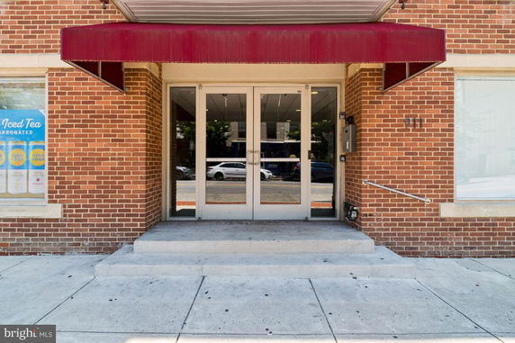 Front view of a brick building entrance with glass double doors and an awning.