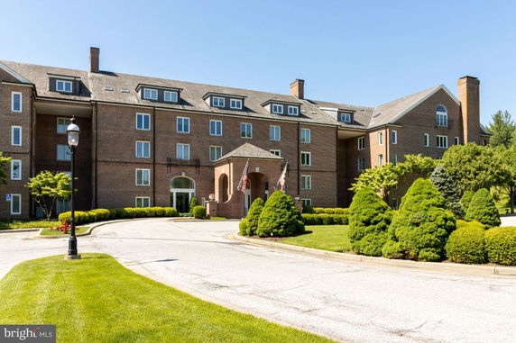 Front view of a multi-story brick building with landscaped entrance and multiple windows.