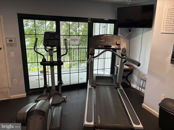 Indoor area with gym equipment including a treadmill and elliptical machine near a large window.