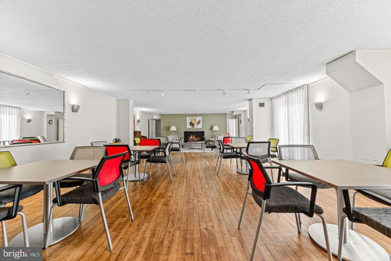 Indoor club house area with tables and chairs, featuring a fireplace and a large mirror on the wall.