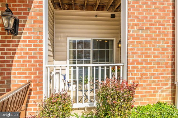 View of a house with a small porch area and sliding glass doors, enclosed by a white railing.