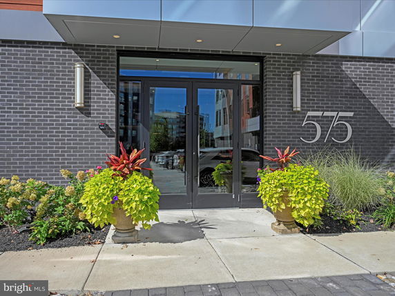 Front view of a building entrance with large glass doors and decorative planters.