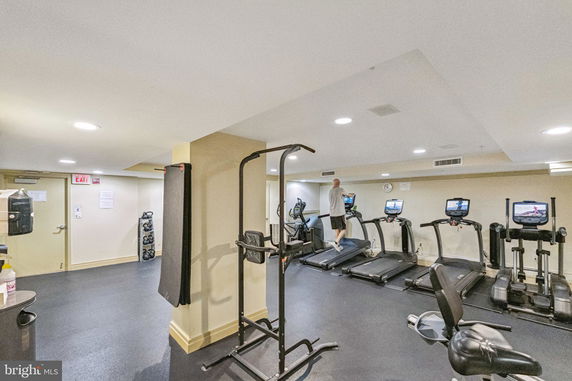 Interior of a gym with exercise equipment and a person on a treadmill.