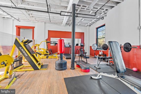 Interior view of a gym with various exercise equipment including weight machines, a punching bag, and treadmills.