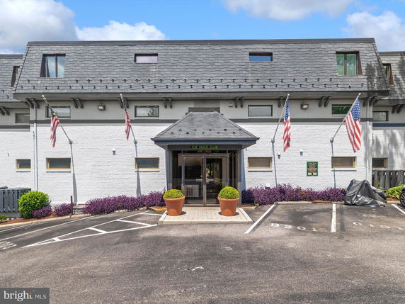 Front view of a building with a sloped roof and flags displayed at the entrance.