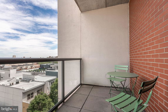 Balcony view with small table and chairs overlooking urban rooftops.