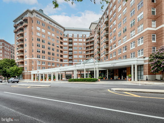 Front view of a multi-story brick building with a prominent entrance and balconies.