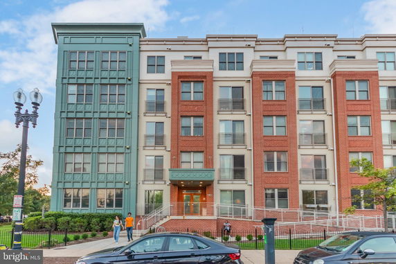 Front view of a multi-story residential building with a brick and teal facade.