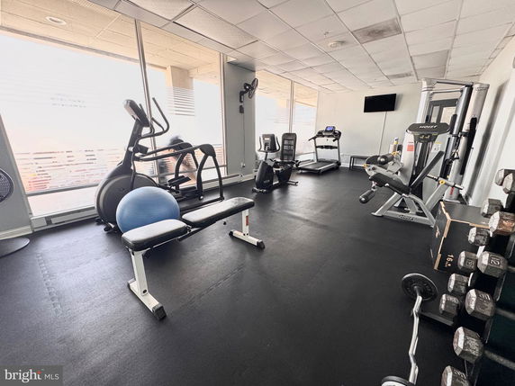 Interior view of a gym with various exercise equipment including treadmills, stationary bikes, and weights.
