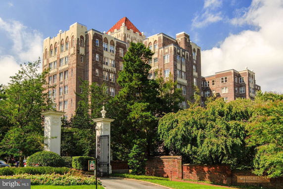 Front view of a multi-story brick building with decorative architectural elements and a gated entrance.