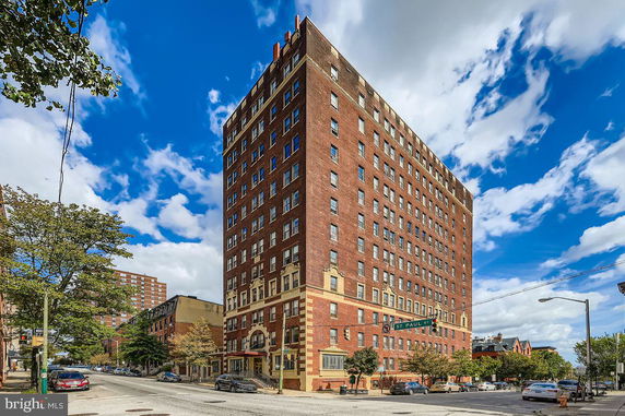 Front view of a multi-story brick building on a street corner.