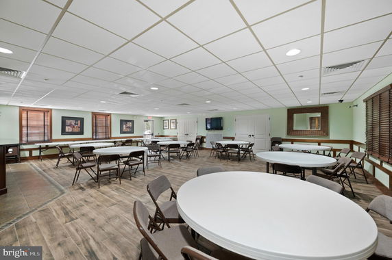 Interior view of a community room with round tables and chairs arranged for a gathering.