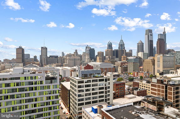 Panoramic view of a city skyline with various high-rise buildings under a blue sky.