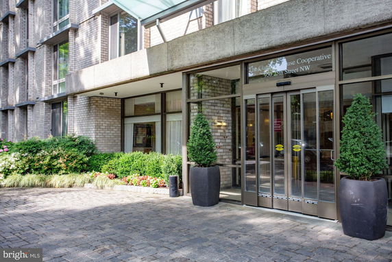Front entrance of a building with large glass doors and potted plants.