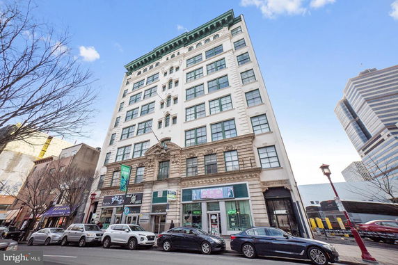 Front view of a multi-story urban building with retail spaces on the ground floor.