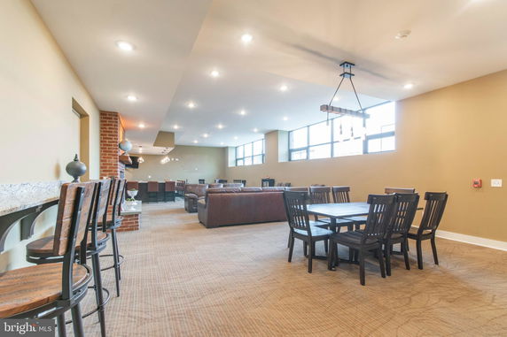 Interior view of a well-lit club house with seating areas and dining tables.