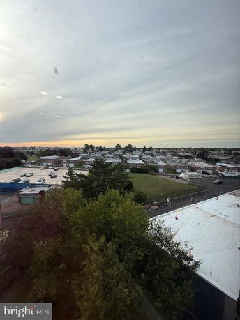 Wide angle view of a suburban area from a high vantage point, showing rooftops and green spaces.