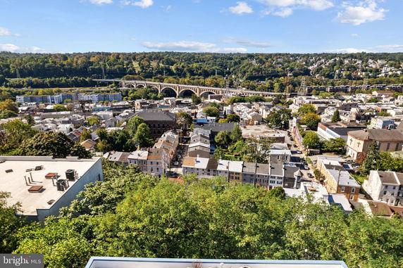 Aerial panoramic view of a residential area with a large bridge and green hills in the background.