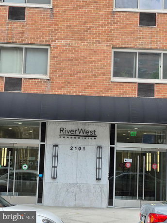 Front view of a brick condominium building with glass entrance doors.