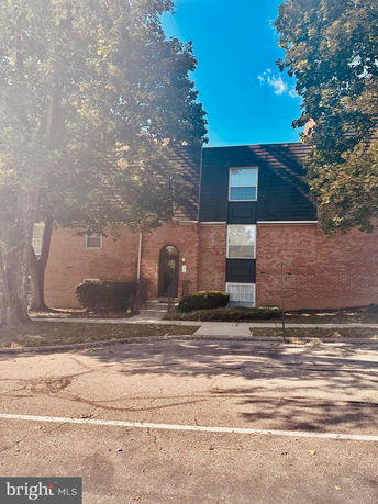 Front view of a multi-story brick building with a sloped roof and large windows.