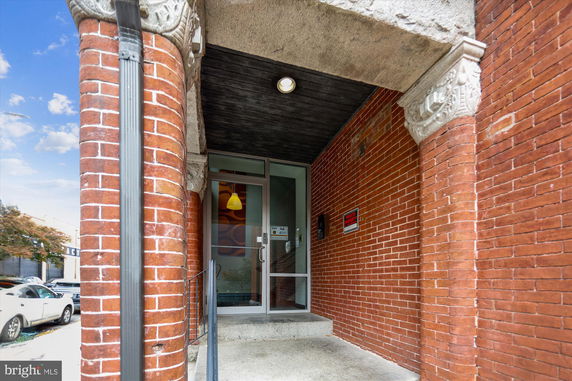 Front view of a building entrance with brick columns and a glass door.