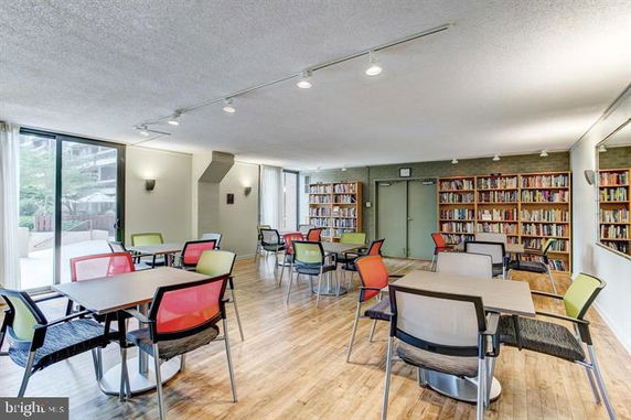 Room with tables, chairs, and bookshelves along the walls.