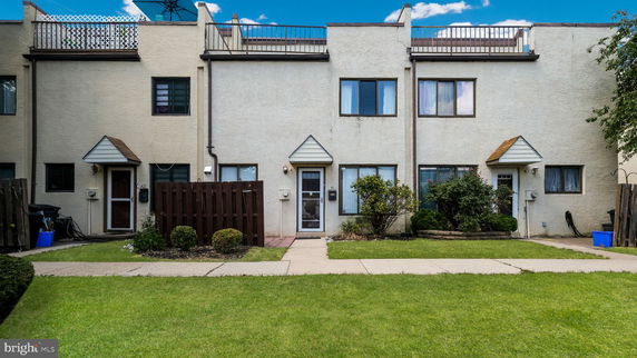 Front view of a multi-story townhouse with small entrances and rooftop balcony.
