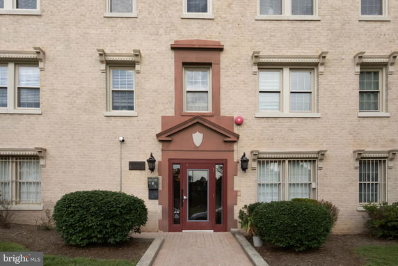 Front view of a multi-story brick building entrance with decorative trim around the doorway.