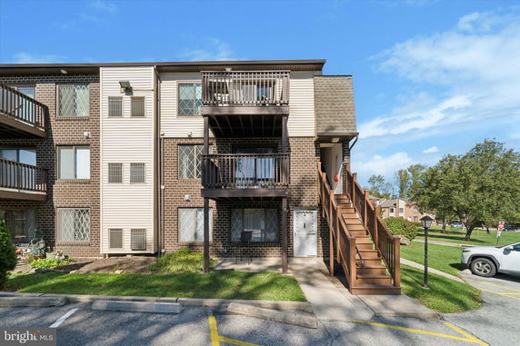Front view of a three-story building with brick and siding exterior and balconies.