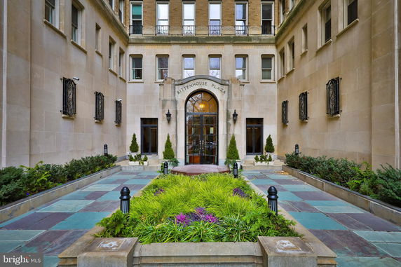 Front view of a building with a landscaped entrance and stone facade.
