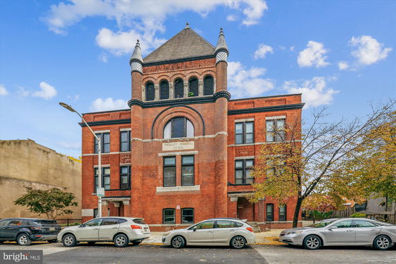 Front view of a historic brick building with a tower and arched windows.