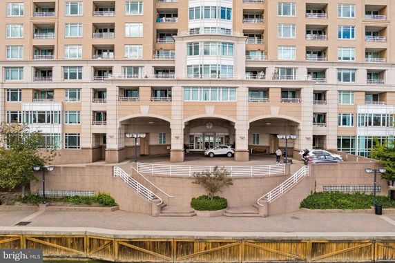 Front view of a multi-story residential building with balconies and parking area.