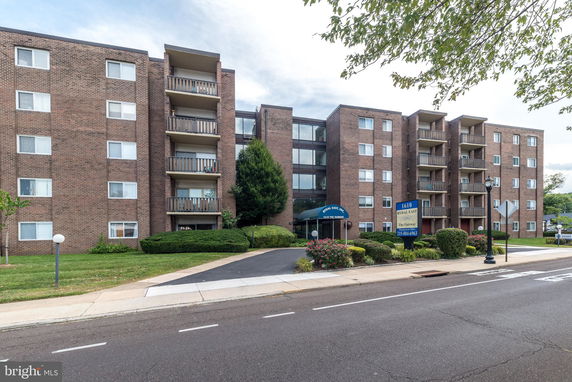 Front view of a multi-story brick apartment building with balconies.